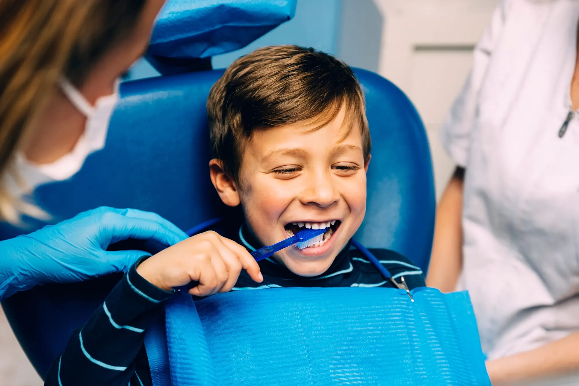 A dentist showing a young boy how to brush his teeth
