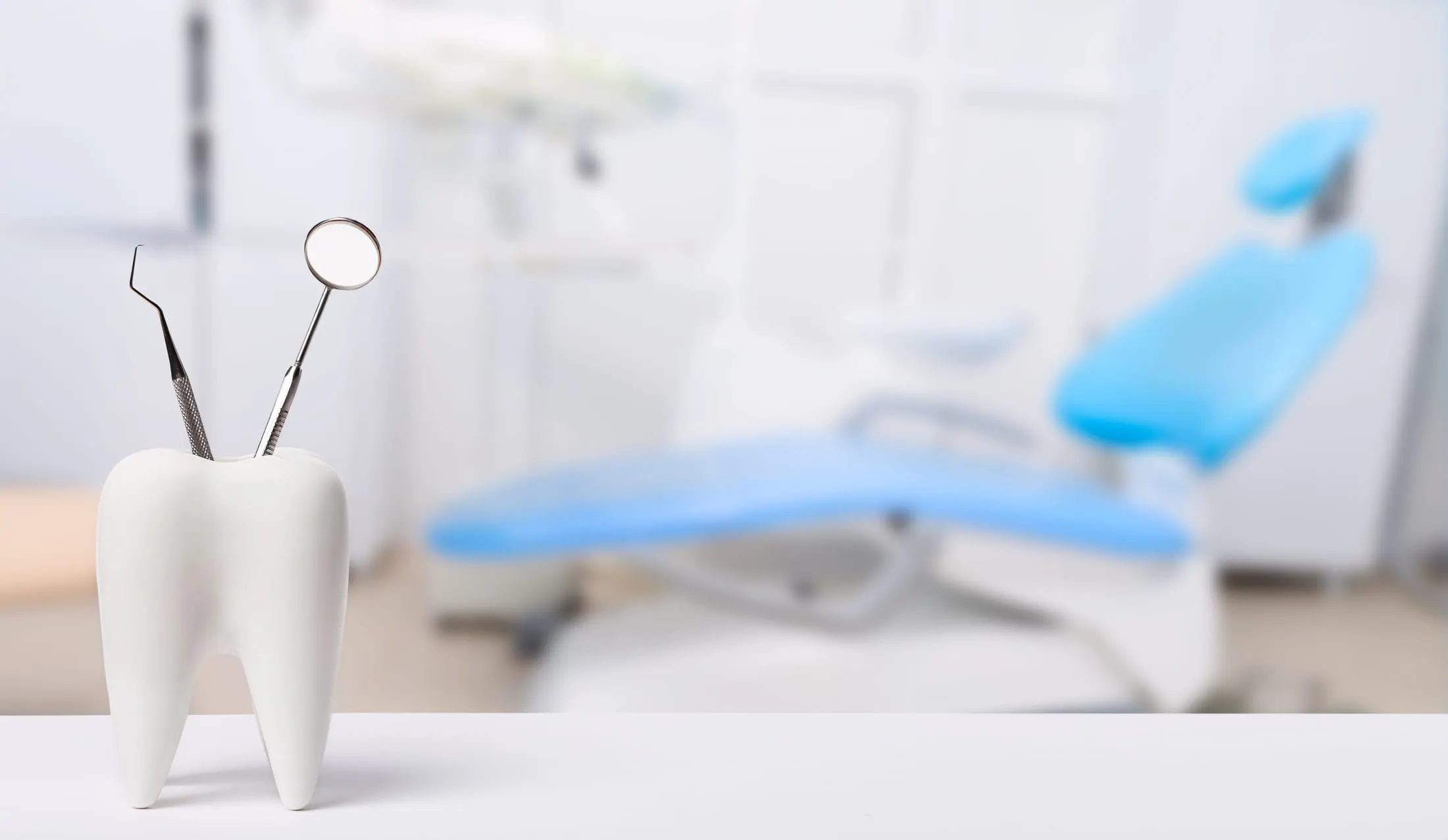A dental mirror and probe in a model tooth, with a treatment chair behind